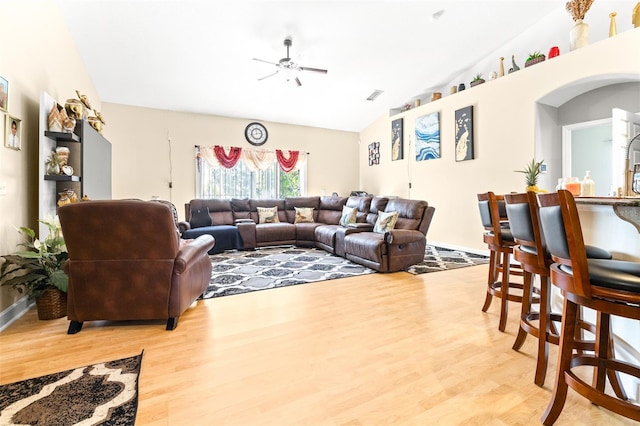 living room featuring ceiling fan, light wood-type flooring, and vaulted ceiling