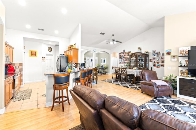 living room featuring ceiling fan, high vaulted ceiling, and light tile patterned floors