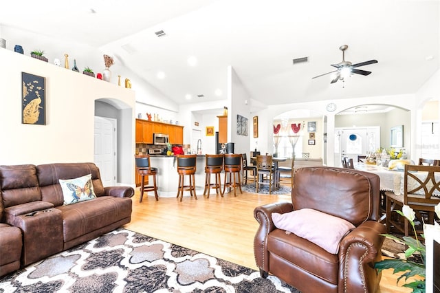 living room featuring ceiling fan, light wood-type flooring, and vaulted ceiling