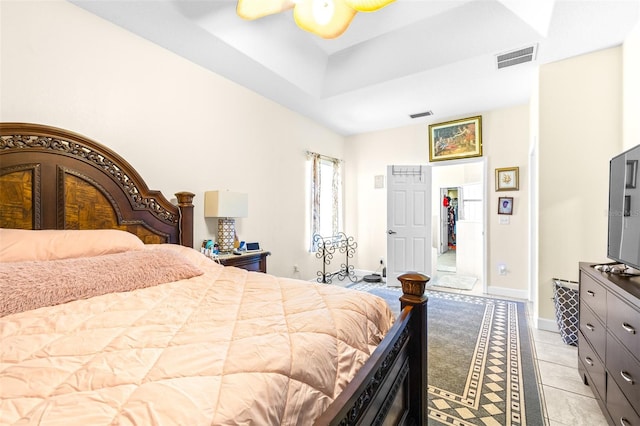 bedroom featuring light tile patterned flooring, ceiling fan, and a raised ceiling