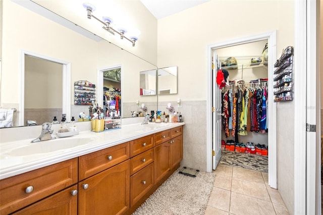 bathroom featuring tile walls, tile patterned floors, and dual bowl vanity