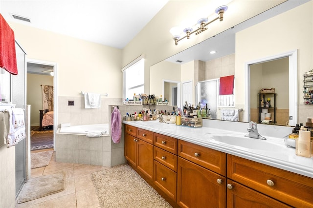 bathroom with double sink vanity, tiled bath, and tile patterned flooring