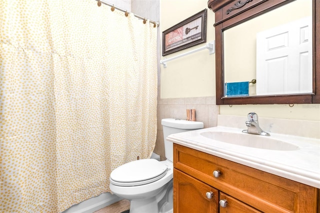 bathroom with tile walls, toilet, and vanity