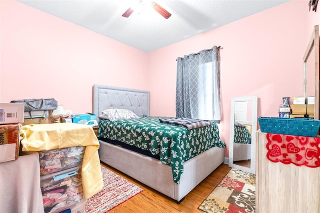 bedroom with ceiling fan, light hardwood / wood-style flooring, and a textured ceiling