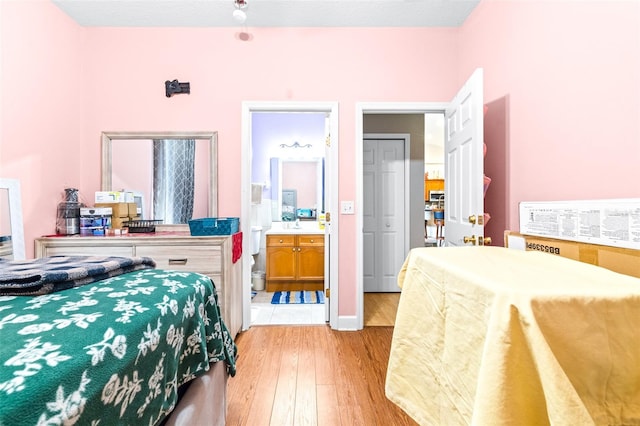 bedroom featuring light wood-type flooring and connected bathroom