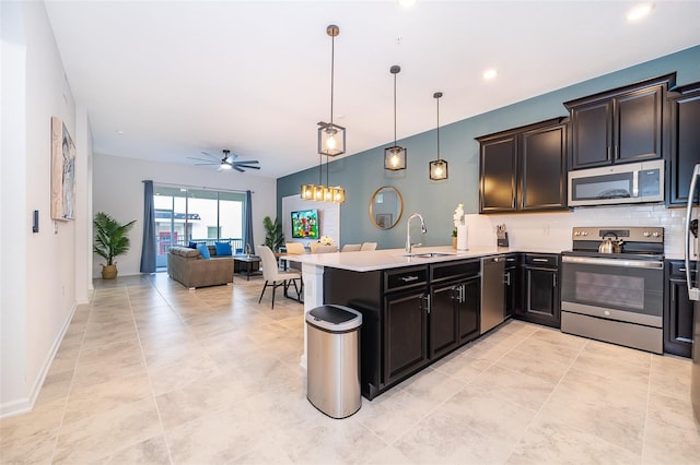 kitchen featuring a peninsula, appliances with stainless steel finishes, light countertops, and a sink