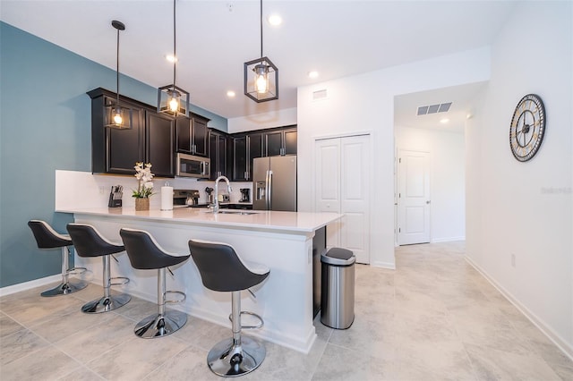 kitchen featuring stainless steel appliances, a sink, visible vents, light countertops, and pendant lighting