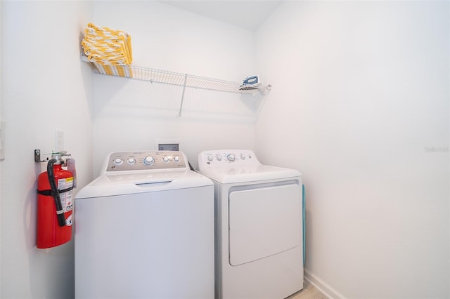 clothes washing area featuring laundry area, baseboards, and washer and clothes dryer