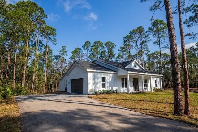 modern farmhouse with a garage, covered porch, and a front lawn