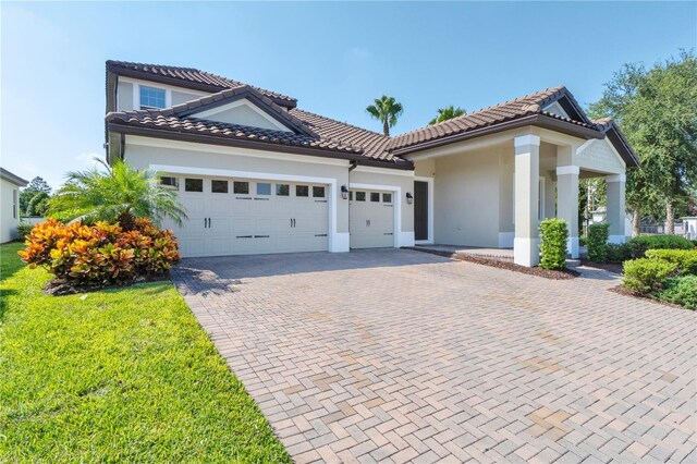 mediterranean / spanish house with a garage and a front lawn