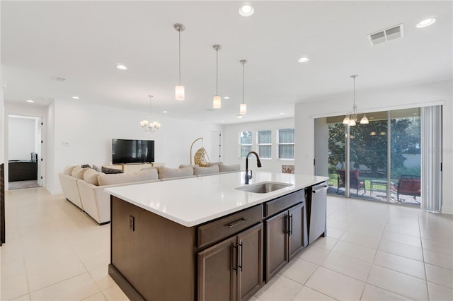 kitchen with an island with sink, hanging light fixtures, a notable chandelier, sink, and dishwasher