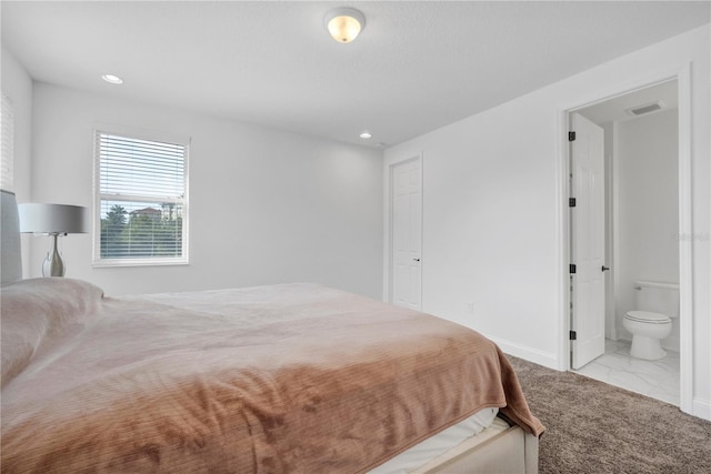 bedroom featuring ensuite bathroom and light colored carpet