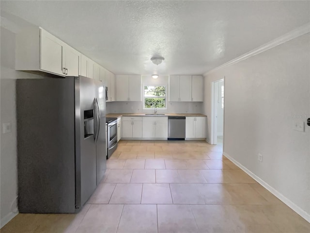 kitchen with white cabinets, baseboards, stainless steel appliances, and a sink