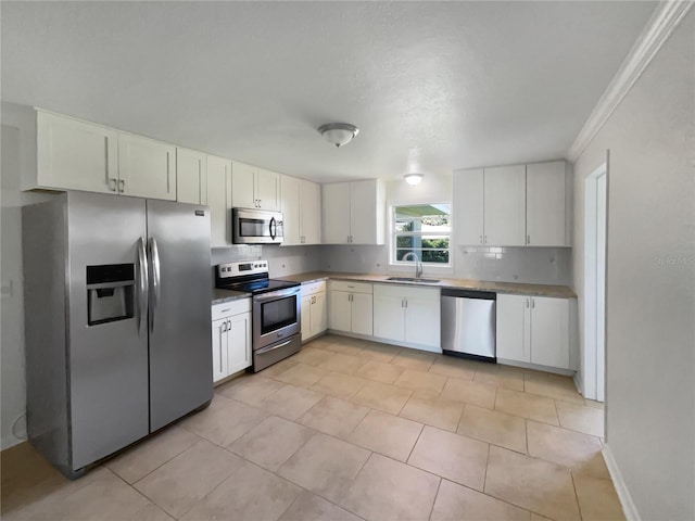 kitchen featuring tasteful backsplash, light countertops, appliances with stainless steel finishes, white cabinets, and a sink