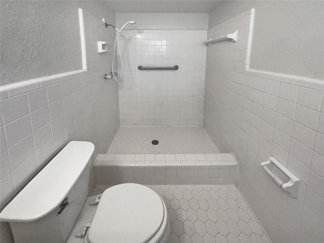 full bath with a wainscoted wall, toilet, a shower stall, and tile walls