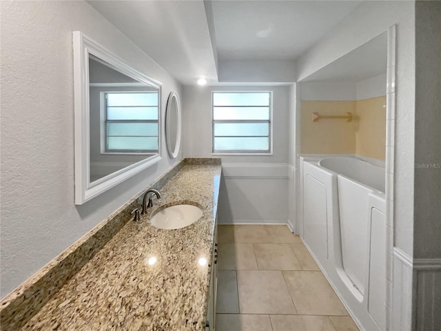 full bathroom featuring a wealth of natural light, vanity, a bath, and tile patterned floors