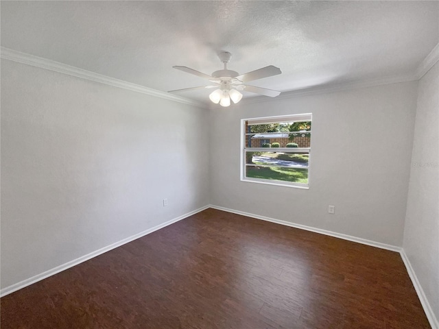 spare room featuring dark wood-type flooring, ceiling fan, baseboards, and ornamental molding