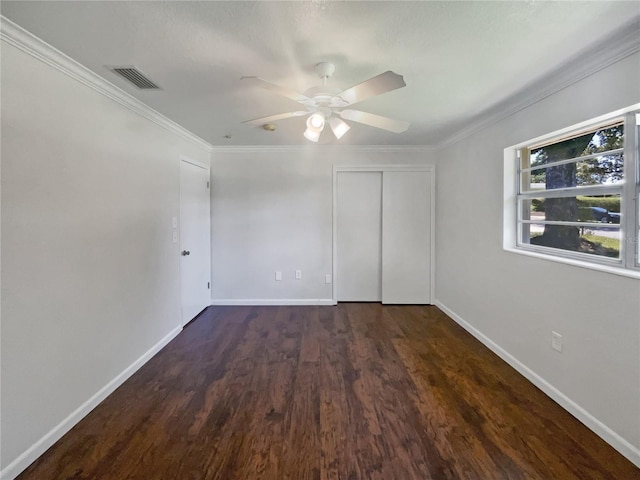 unfurnished bedroom featuring visible vents, baseboards, ornamental molding, a closet, and dark wood-style floors