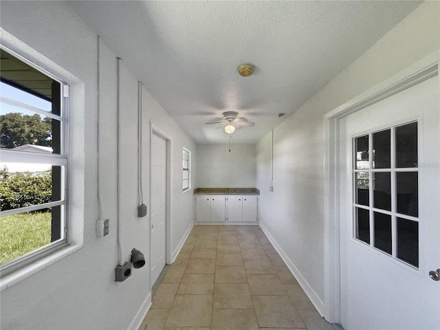 laundry room featuring ceiling fan, baseboards, and light tile patterned floors