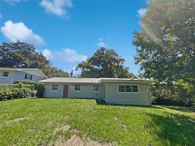 back of property with metal roof and a lawn