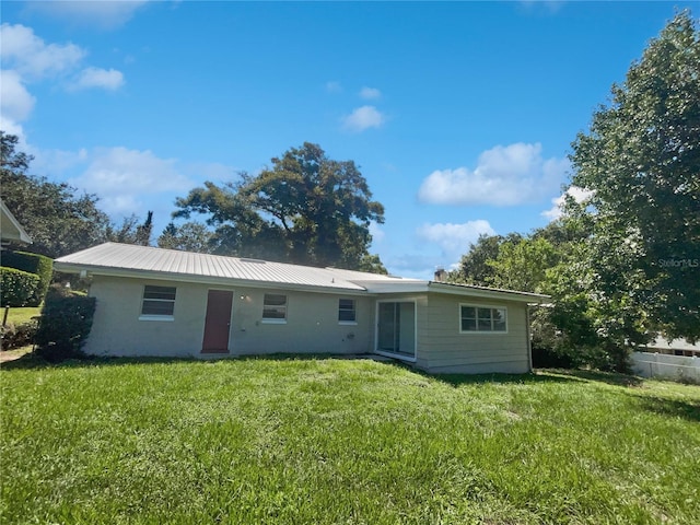 back of property featuring metal roof and a yard