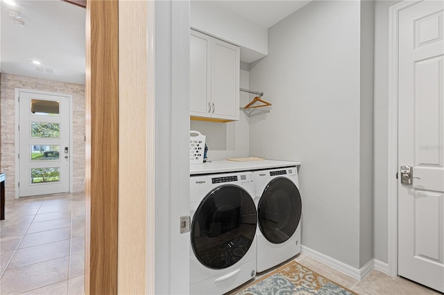 washroom with light tile patterned floors, washer and clothes dryer, and cabinets