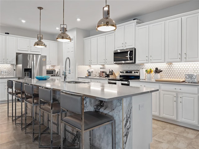 kitchen featuring appliances with stainless steel finishes, a kitchen island with sink, light tile patterned floors, and backsplash