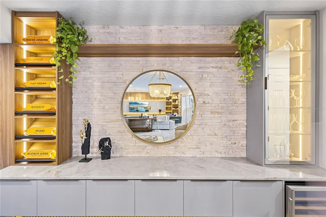 exterior details with beverage cooler, an inviting chandelier, and a textured ceiling