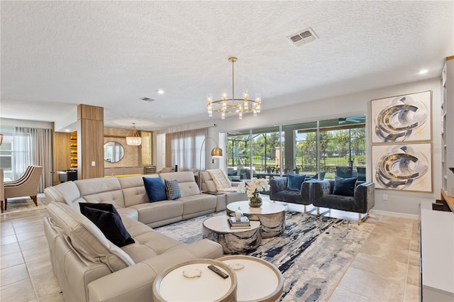 tiled living room featuring a textured ceiling, plenty of natural light, and an inviting chandelier