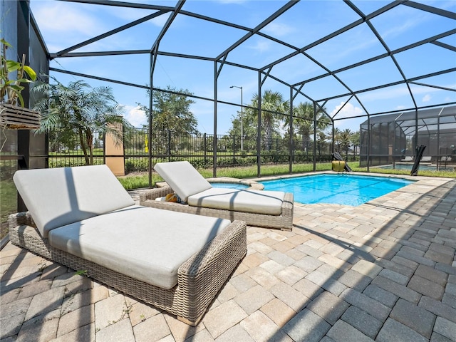 view of swimming pool featuring glass enclosure and a patio