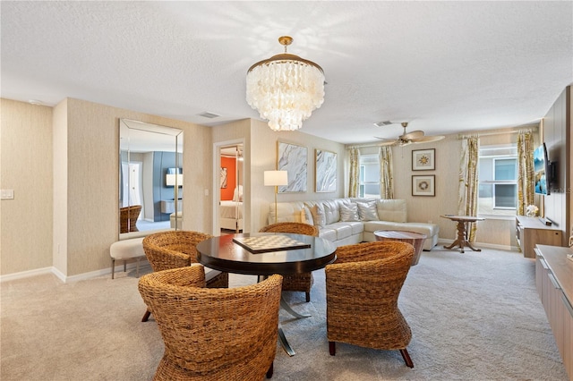 dining area with light colored carpet, a textured ceiling, and ceiling fan with notable chandelier