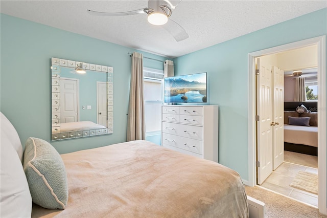 bedroom featuring ceiling fan, light tile patterned floors, and a textured ceiling