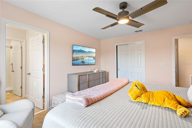 bedroom featuring ceiling fan, a closet, ensuite bathroom, and light colored carpet