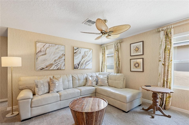 living room featuring ceiling fan, light carpet, and a textured ceiling