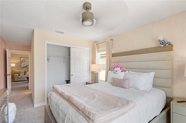 bedroom with light colored carpet, a closet, a textured ceiling, and ceiling fan