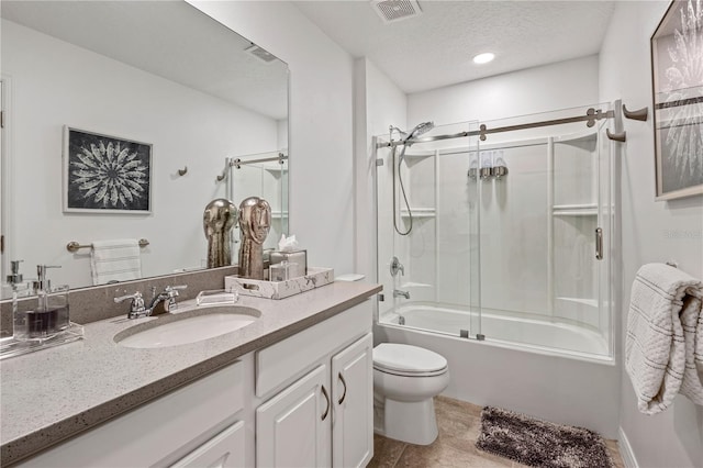 full bathroom with tile patterned floors, a textured ceiling, shower / bath combination with glass door, vanity, and toilet