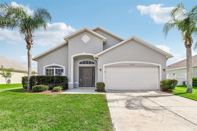 mediterranean / spanish house with a garage, concrete driveway, a front lawn, and stucco siding