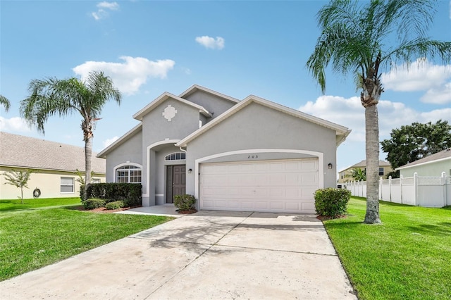 mediterranean / spanish home featuring an attached garage, fence, driveway, stucco siding, and a front lawn