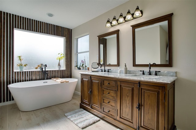 bathroom with hardwood / wood-style flooring, a tub to relax in, and dual bowl vanity