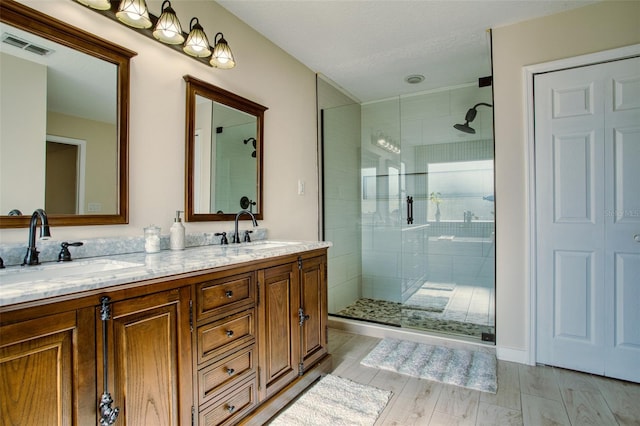 bathroom featuring double vanity and a shower with door