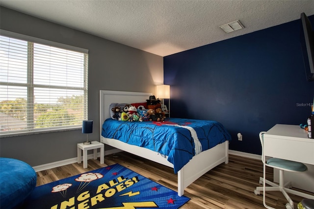 bedroom featuring a textured ceiling, hardwood / wood-style floors, and multiple windows