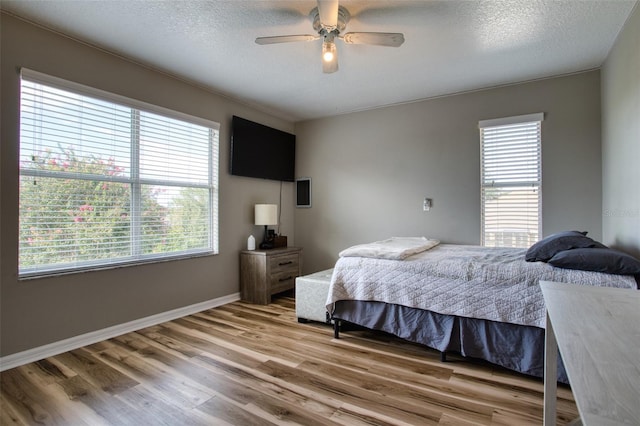 bedroom featuring multiple windows, wood-type flooring, and ceiling fan