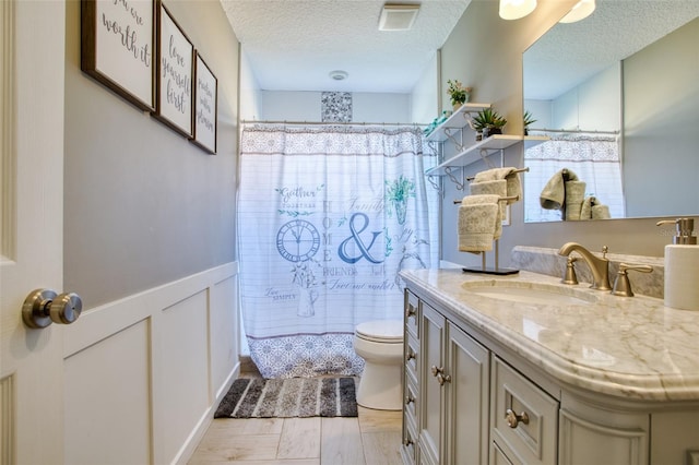 bathroom with tile patterned floors, toilet, a textured ceiling, and vanity