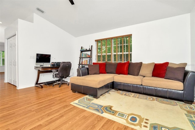 living room featuring lofted ceiling and light hardwood / wood-style floors