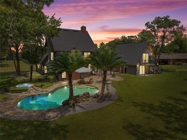 pool at dusk with a patio and a lawn