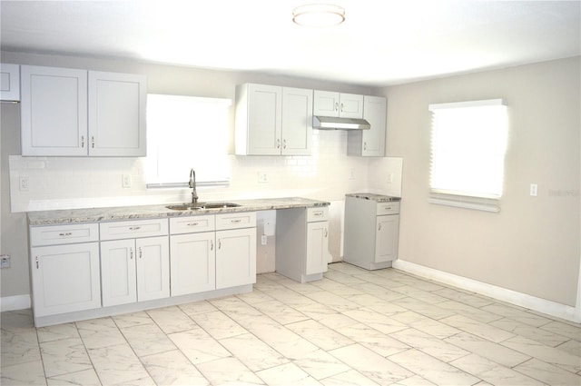 kitchen featuring light stone counters, backsplash, and sink