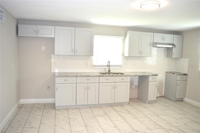 kitchen featuring light stone counters, backsplash, sink, and white cabinetry