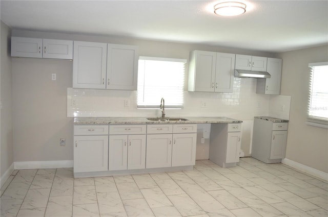 kitchen featuring light stone counters, backsplash, plenty of natural light, and sink