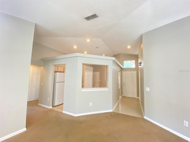 interior space with vaulted ceiling, a textured ceiling, and light carpet