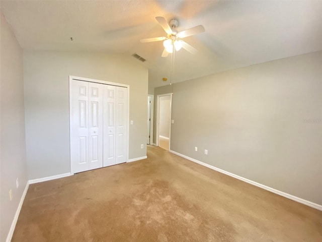 unfurnished bedroom featuring carpet, lofted ceiling, a closet, and ceiling fan